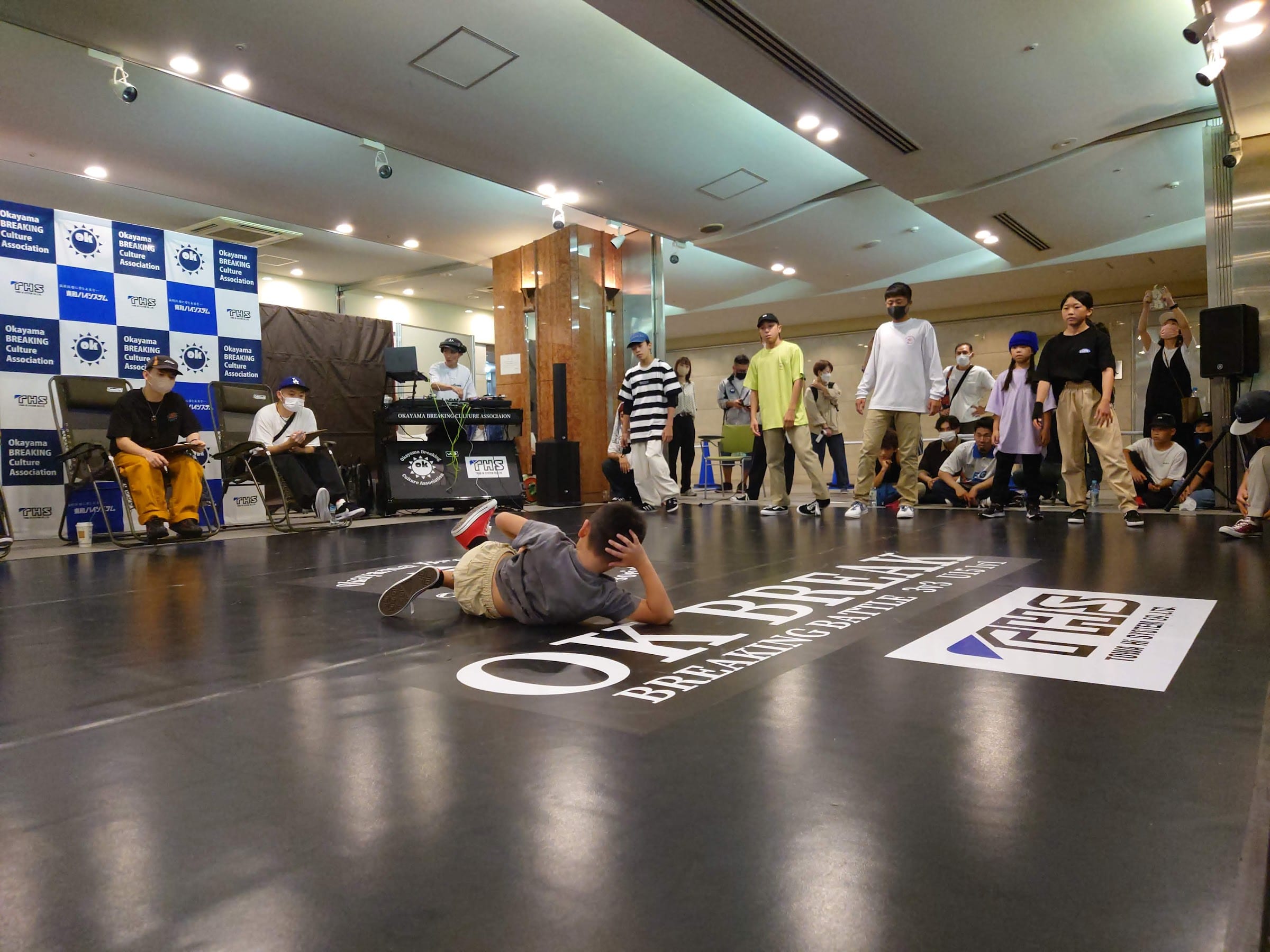 OK BREAK 床ロゴの上で横臥するダンサー