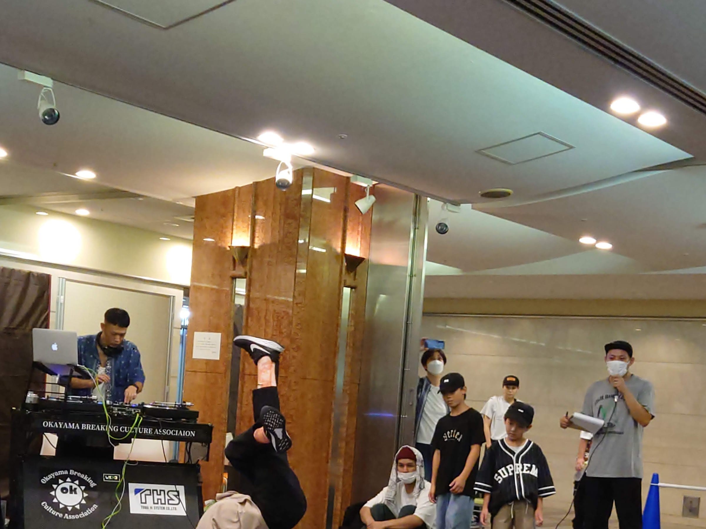 DJ ブースの後ろで逆立ちフリーズを決めるダンサー