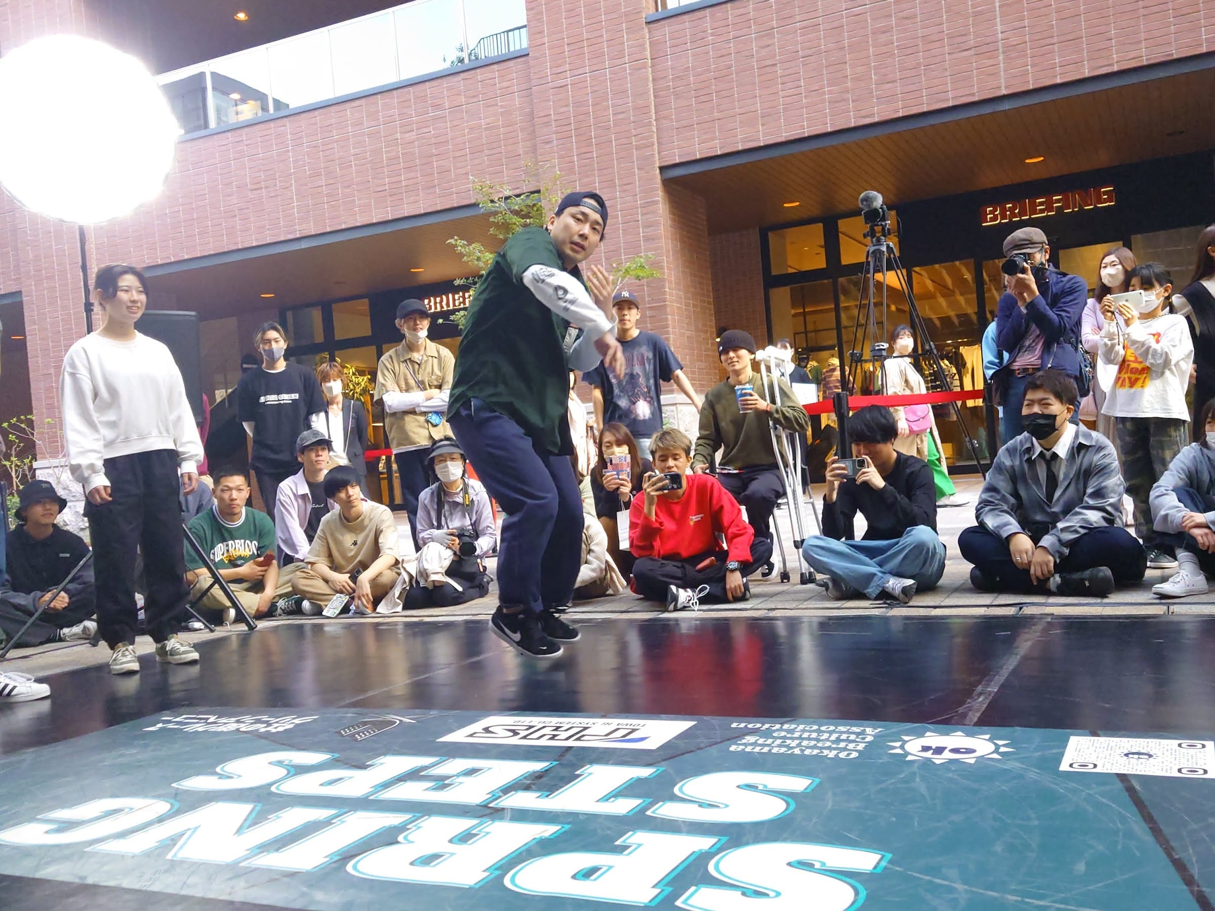 SPRING STEPS の床ロゴの上で跳ねる b-boy