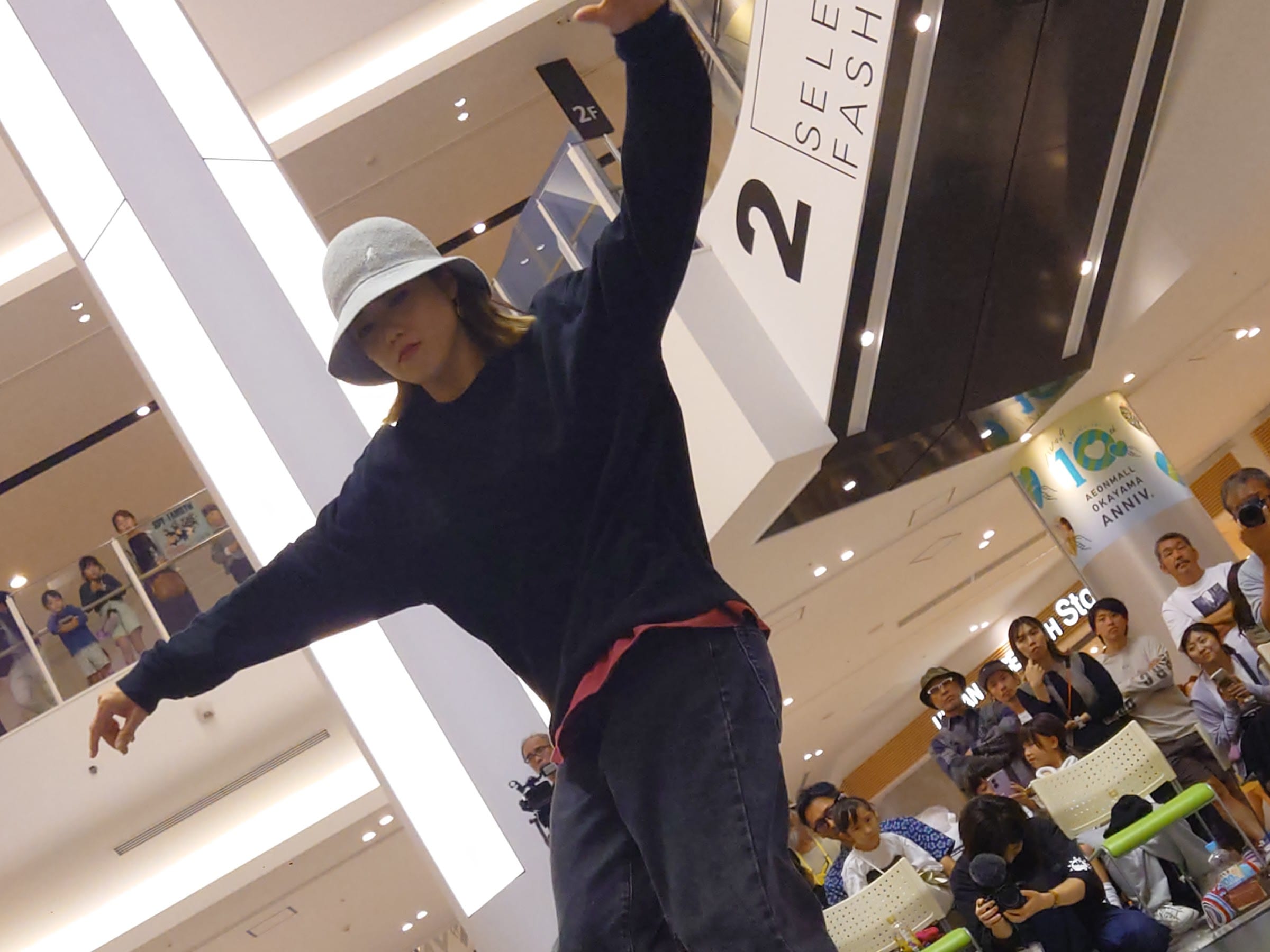白いハットの B-Girl が FUTURE 看板を背景に技を決める